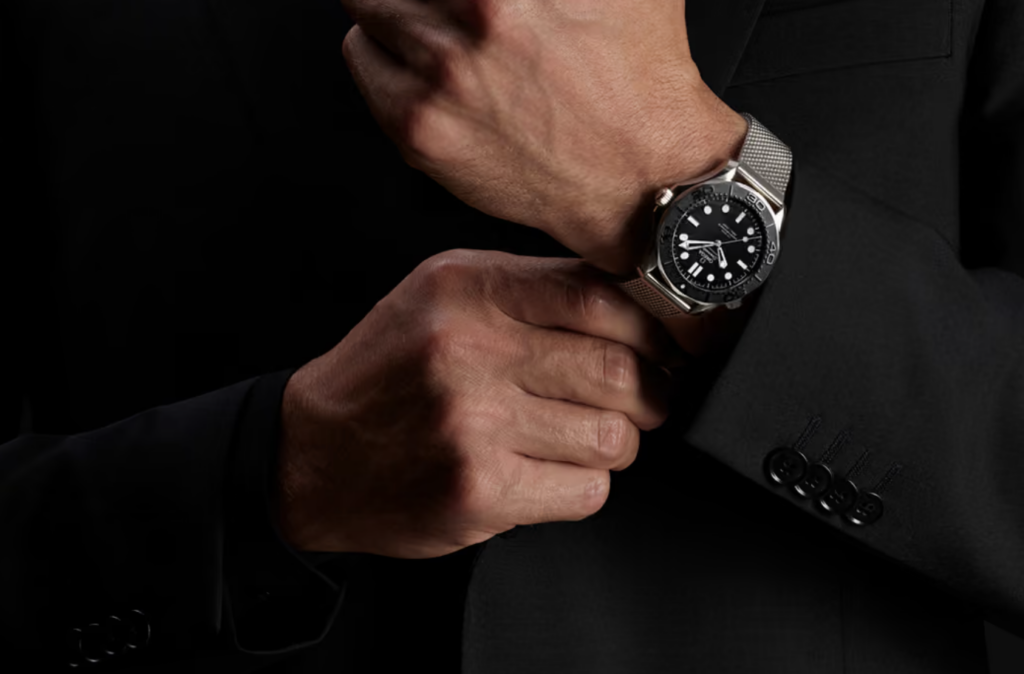 Man in a dark suit wearing the Omega Seamaster Diver 300M Spectre Edition on a steel mesh bracelet
